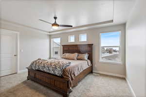 Carpeted bedroom featuring a raised ceiling, a textured ceiling, and ceiling fan