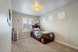 Bedroom with a textured ceiling and light colored carpet