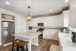 Kitchen with white cabinets, stainless steel appliances, a center island, pendant lighting, and sink