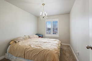 Bedroom with an inviting chandelier and carpet