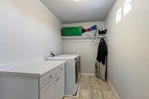 Washroom featuring a textured ceiling, cabinets, and separate washer and dryer