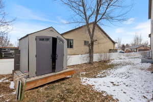 Snow covered back of property with a shed