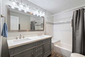 Bathroom with shower / bathtub combination with curtain, wood-type flooring, and vanity