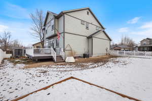 Snow covered house featuring central AC, a shed, and a wooden deck