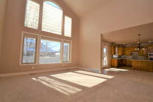 Unfurnished living room featuring high vaulted ceiling and light carpet