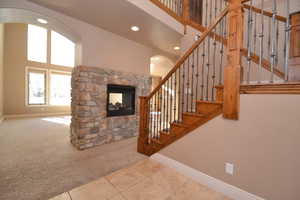 Stairs featuring a high ceiling, carpet, and a stone fireplace