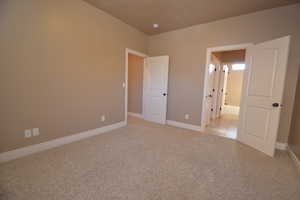 Unfurnished bedroom with light colored carpet and ensuite bath