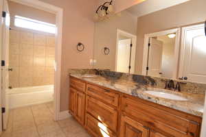 Bathroom featuring vanity, tile patterned flooring, and tiled shower / bath combo