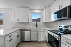 Kitchen with sink, white cabinetry, kitchen peninsula, and appliances with stainless steel finishes