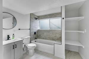 Full bathroom with toilet, tiled shower / bath, and vanity