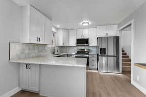 Kitchen featuring stainless steel appliances, white cabinets, sink, and kitchen peninsula