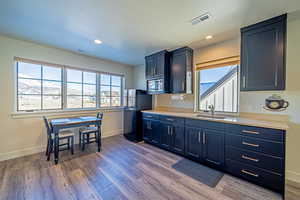 Kitchen with black refrigerator, hardwood / wood-style floors, stainless steel microwave, and sink