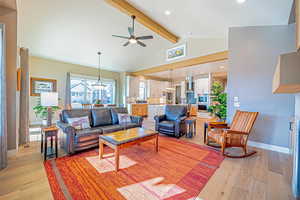 Living room with beam ceiling, light wood-type flooring, high vaulted ceiling, and ceiling fan