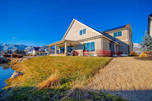 Back of house with a mountain view, solar panels, a pergola, and a lawn