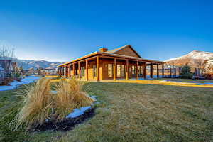 Rear view of property with a mountain view and a lawn