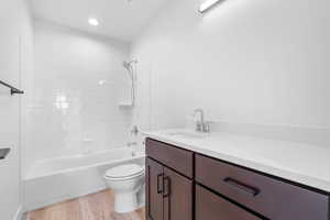 Full bathroom with toilet, vanity, hardwood / wood-style flooring, and tiled shower / bath