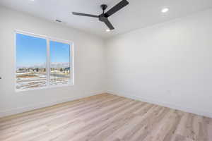 Empty room featuring ceiling fan, light wood-type flooring, and a mountain view