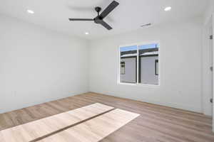 Empty room with ceiling fan and light hardwood / wood-style flooring