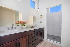 Bathroom featuring hardwood / wood-style floors, vanity, and a tile shower