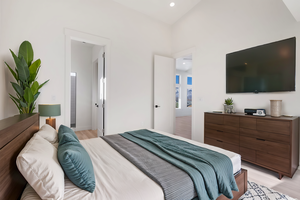 Bedroom with ensuite bathroom, vaulted ceiling, and light hardwood / wood-style flooring