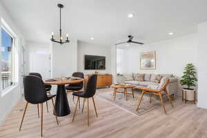 Dining space with ceiling fan with notable chandelier and light hardwood / wood-style flooring