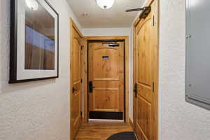 Corridor with a textured ceiling, hardwood / wood-style floors, and electric panel