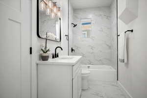 Full bathroom featuring tiled shower / bath, vanity, and toilet