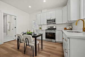 Kitchen featuring light wood-type flooring, appliances with stainless steel finishes, white cabinetry, and sink