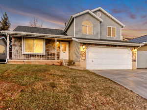 Front of property with a garage, a porch, and a yard