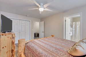 Bedroom with a textured ceiling, ceiling fan, a closet, and carpet