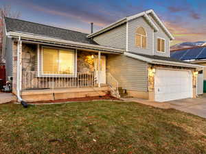 View of front of house with a garage, covered porch, and a lawn