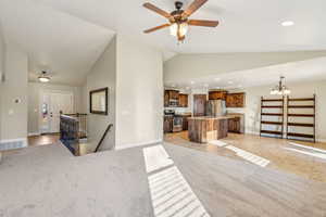 Interior space with decorative light fixtures, light carpet, a kitchen island, a breakfast bar, and appliances with stainless steel finishes