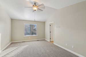 Empty room featuring vaulted ceiling, light colored carpet, and ceiling fan