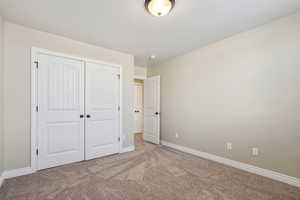 Unfurnished bedroom with light colored carpet and a closet