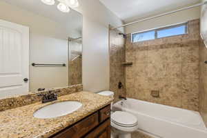 Full bathroom with toilet, tiled shower / bath, and vanity