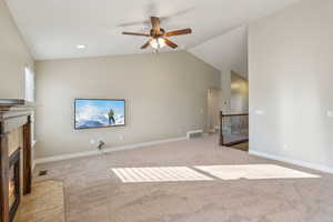 Unfurnished living room with a high end fireplace, light carpet, ceiling fan, and vaulted ceiling