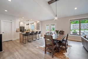 Dining space with french doors, light hardwood / wood-style floors, lofted ceiling with beams, and sink