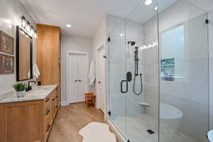 Bathroom with a shower with door, vanity, and hardwood / wood-style floors