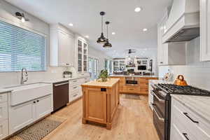 Kitchen featuring white cabinets, double oven range, wood counters, and custom range hood