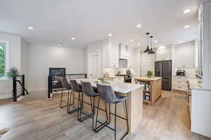 Kitchen with custom exhaust hood, pendant lighting, a kitchen island, white cabinetry, and premium appliances