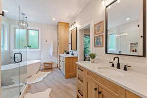 Bathroom featuring an inviting chandelier, shower with separate bathtub, wood-type flooring, and vanity