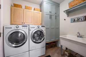 Laundry area with washing machine and dryer, cabinets, and dark hardwood / wood-style floors