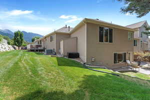 Rear view of property featuring a yard, cooling unit, and a deck with mountain view