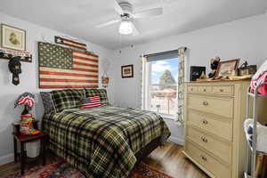 Bedroom with a textured ceiling, ceiling fan, and light hardwood / wood-style floors