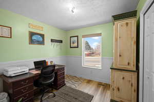 Office with a textured ceiling and light hardwood / wood-style flooring