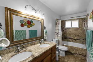 Full bathroom featuring toilet, shower / bath combo, and vanity