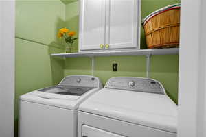 Laundry area featuring washing machine and dryer and cabinets