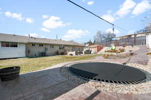 Rear view of house featuring a patio area, a yard, a storage shed, cooling unit, and a trampoline