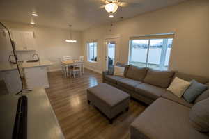 Living room with ceiling fan with notable chandelier, sink, and dark hardwood / wood-style floors