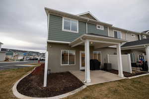 Rear view of house featuring a patio, central air condition unit, and a lawn